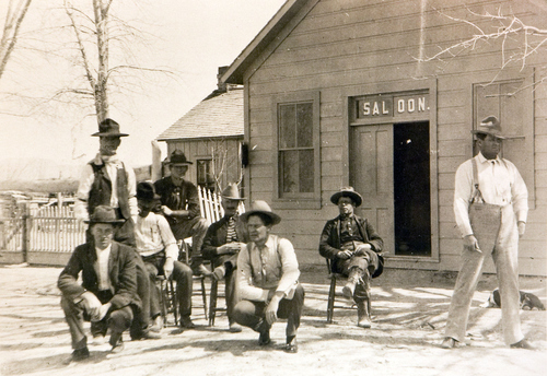 This is the saloon that was the hangout of The Wild Bunch in 1889. The man standing beside the tree is Harry Longbaugh (The Sundance Kid) and the man sitting on the chair beside him is Butch Cassidy. Courtesy of the Utah Historical Society