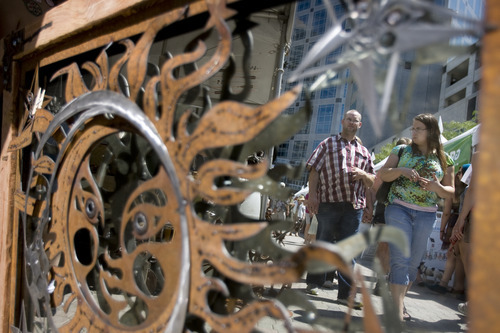Kim Raff | The Salt Lake Tribune
People walking by are reflected in a mirror at the Raw Materials Sculpture and Design booth during the 4th annual Craft Lake City Utah's DIY Festival at the Gallivan Center in Salt Lake City, Utah on August 11, 2012.