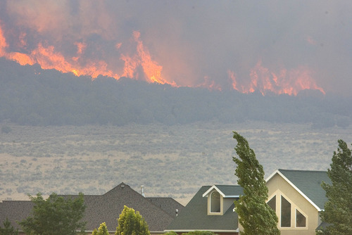 Paul Fraughton | Tribune file photo
Wildfires in Utah already have cost $50 million, burning more than 422,000 acres around the state. The Legislature expects to face a $21 million bill and the feds have spent about $34 million. The file photo shows the lightning-caused  Pinion Fire burning behind homes in Eagle Mountain earlier this month.