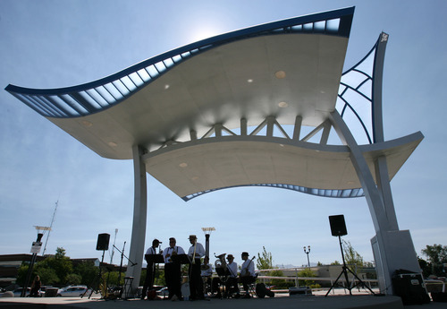 Steve Griffin | The Salt Lake Tribune
A band plays under a shade structure at West Valley City's new Fairbourne Station Promenade on Thursday. The park has interactive features, including a scale that will depict the weight of a group of people standing on it in terms of chickens, cows and bales of hay.