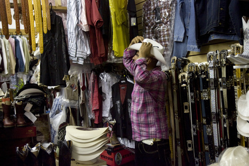 Kim Raff | The Salt Lake Tribune
Vasmin clothing store owner Rogelio Vasmin tries on a cowboy hat in his store in the Azteca Indoor Bazaar and Swap Meet in West Valley City.