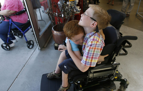Francisco Kjolseth  |  The Salt Lake Tribune
Carter Veldevere, a 6th grader from Hayden Peak Elementary in West Jordan who has spinal muscular atrophy, gets a bear hug from his brother Aiden, 4, during a special event at Smith's at 455 S. 500 E., in Salt Lake City on Tuesday. The 10-year-old received a sponsorship from Milk-Bone and Smith's Food & Drug, and will be matched with a free service dog some time in the next year.