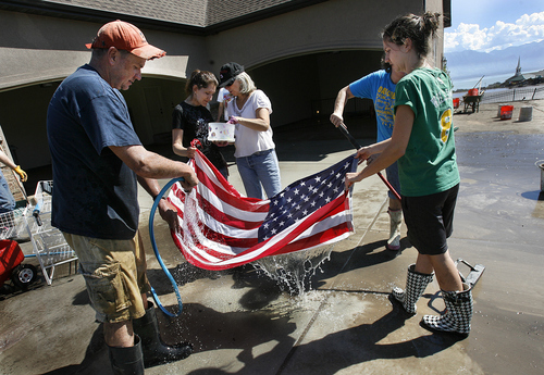 Scott Sommerdorf  |  The Salt Lake Tribune             
Volunteers help clean items, including this flag saved from Alan Rencher's flooded garage and basement. Neighbors and other volunteers pitched in to help the homeowners affected by the flood near the intersection of Apaloosa and Weatherby drives in Saratoga Springs, Sunday, Sept. 2, 2012.