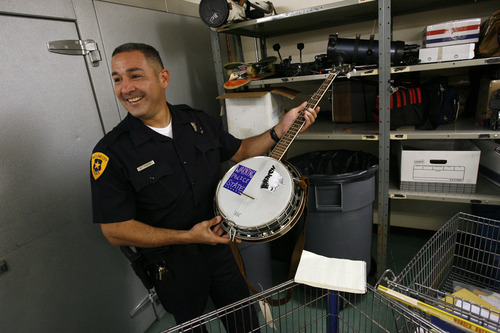 Francisco Kjolseth  |  The Salt Lake Tribune
Detective Mike Hamideh with the Salt Lake City Police department smiles over a banjo initially kept for safe keeping with a sticker that reads 