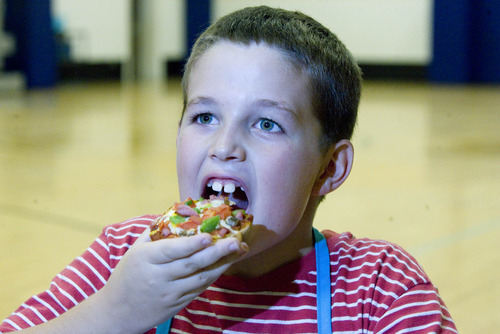 Paul Fraughton | The Salt Lake Tribune
Elijah Martinez takes a big bite from his healthy English Muffin Pizza he made at a cooking class at the the Murray Boys and Girls Club.
