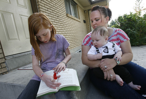 Scott Sommerdorf  |  The Salt Lake Tribune              
Nina Neubert listens as her daughter Jasmyn Neubert, 9, reads a book after school, while holding her 4-month-old son, Jaiden, on the front porch of their Orem home, Friday, October 19, 2012. Neubert says she was misled about the adoption process by DCFS, causing her to lose the opportunity to adopt her nieces and nephew from foster care due to a missed deadline. The children will likely now be adopted by a foster family.