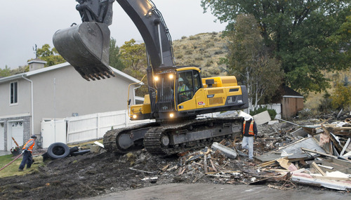 Al Hartmann  |  The Salt Lake Tribune
Backhoe finishes knocking down a house on Springhill Drive in North Salt Lake on Tuesday, Oct. 23 while the house at left will remain.   With the help of a federal grant, North Salt Lake is stabilizing the Springhill landslide by demolishing homes in the area, shoring up others and and turning the site into an open-space park.