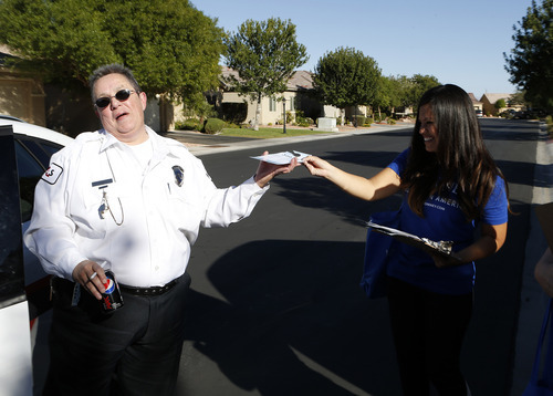 Utah republican Linda Patiño, right, offers early voting information to security guard Lee Rose after Rose cited her for canvasing homes in Las Vegas on Saturday, Oct. 20, 2012. (Isaac Brekken for the Salt Lake Tribune)