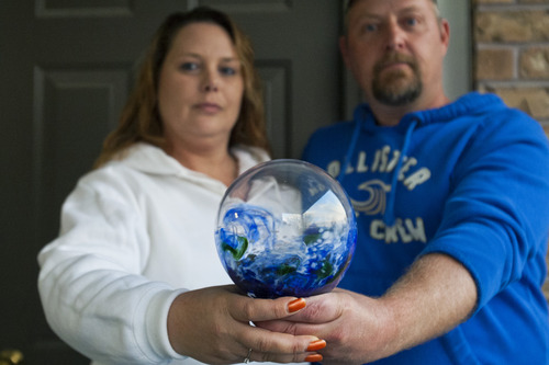 Chris Detrick  |  The Salt Lake Tribune
Shaun and Jennifer Peterson hold memorial glass at their home on Thursday. Jennifer went to a Deseret Industries a few days ago and picked up a blown-glass piece for $3. When she went to the Internet to find out its value, she realized it's a "memorial glass," where someone's ashes are mixed into a glass piece. She is hoping to find the rightful owner who inadvertently gave away their family member.