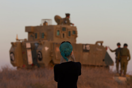 A woman photographs Israeli soldiers on top an armored personal carrier close to the Israel Gaza Border, southern Israel,Thursday, Nov. 15, 2012. Israel's prime minister says the army is prepared for a "significant widening" of its operation in the Gaza Strip. Benjamin Netanyahu told reporters on Thursday that Israel has "made it clear" it won't tolerate continued rocket fire on its civilians. (AP Photo/Ariel Schalit)