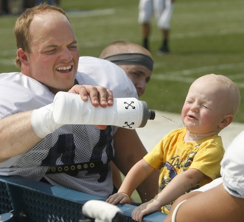 Rick Egan  | The Salt Lake Tribune 

BYU linebacker Brandon Ogletree gives his 11-month-old son Luke a drink of water on the BYU bench after the football scrimmage at LaVell Edwards Stadium on Aug. 16, 2012.