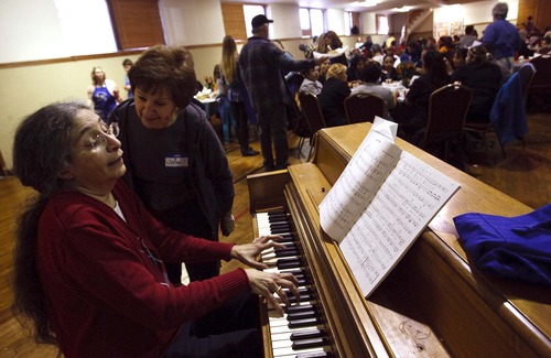 Leah Hogsten  |  The Salt Lake Tribune
Jo Ann Pullos, left, greets her friend Toni Mae Dwyer as she plays "Home On The Range" and other patriotic songs on the piano Thursday. Over 250 volunteers and parishioners at the Holy Trinity Green Orthodox Cathedral serve Thanksgiving dinner to people in need, which included a clothing and food donation drive, in Salt Lake City.