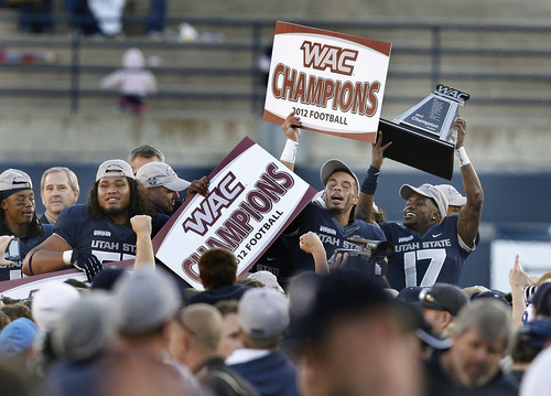 Scott Sommerdorf  |  The Salt Lake Tribune              
Utah State Aggies CB Will Davis (17), right, hoists the WAC trophy as his team mate WR Matt Austin holds aloft a WAC Champions sign after the win over Idaho. Utah State defeated Idaho 45-9 in Logan, Saturday, November 24, 2012 to become champions of the WAC.