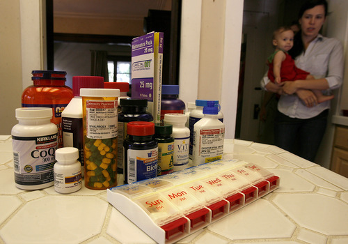 Scott Sommerdorf  |  The Salt Lake Tribune             
Bertrand Might's mother, Cristina, holds her daughter, Victoria, as the medications Bertrand takes daily are displayed on a kitchen counter in the foreground.