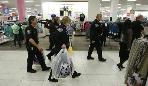 Francisco Kjolseth  |  The Salt Lake Tribune
West Valley City Police officers carry kids clothes as they kick off the West Valley City Giving Tree at Valley Fair Mall on Tuesday, Nov. 27, 2012, benefiting 176 youth from 58 families. Those interested in supporting the program can choose and check out a name from the trees located near the Valley Fair Mall Customer Service Center; service representatives will provide a list of the child's needs and holiday wishes. Shoppers are then asked to return the unwrapped gifts to the desk before Dec. 15. The West Valley City Police Department's Community Services Section started the tradition several years ago when a family they were working with experienced multiple tragedies and were left with no resources for the holidays. The department now coordinates with a local organization that works with low-income families in the city to choose names for the tree.