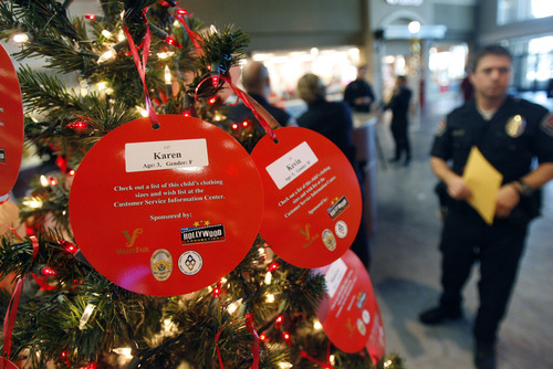 Francisco Kjolseth  |  The Salt Lake Tribune
West Valley City Police officers kick off the West Valley City Giving Tree at Valley Fair Mall on Tuesday, Nov. 27, 2012, benefiting 176 youth from 58 families. Those interested in supporting the program can choose and check out a name from the trees located near the Valley Fair Mall Customer Service Center; service representatives will provide a list of the child's needs and holiday wishes. Shoppers are then asked to return the unwrapped gifts to the desk before Dec. 15. The West Valley City Police Department's Community Services Section started the tradition several years ago when a family they were working with experienced multiple tragedies and were left with no resources for the holidays. The department now coordinates with a local organization that works with low-income families in the city to choose names for the tree.