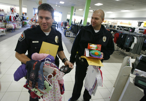 Francisco Kjolseth  |  The Salt Lake Tribune
West Valley City Police officer Devin Novara, left, and Lt. Steve Burke get ready to check out as they kick off the the West Valley City Giving Tree at Valley Fair Mall on Tuesday, Nov. 27, 2012, benefiting 176 youth from 58 families. Those interested in supporting the program can choose and check out a name from the trees located near the Valley Fair Mall Customer Service Center; service representatives will provide a list of the child's needs and holiday wishes. Shoppers are then asked to return the unwrapped gifts to the desk before December 15. The West Valley City Police Department's Community Services Section started the tradition several years ago when a family they were working with experienced multiple tragedies and were left with no resources for the holidays. The department now coordinates with a local organization that works with low-income families in the city to choose names for the tree.
