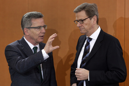German Defence Minister Thomas de Maiziere, left, and German Foreign Minister Guido Westerwelle , right, talk as they arrive for the weekly cabinet meeting at the chancellery in Berlin, Germany, Thursday, Dec. 6, 2012. Germany's Cabinet on Thursday approved sending German Patriot air defense missiles to Turkey to protect the NATO member against possible attacks from Syria, in a major step toward possible Western military role in the Syrian conflict. Defense Minister Thomas de Maiziere told reporters that two batteries with a total of 400 soldiers would be sent to the border area under NATO command for one year, although the deployment could be shortened. The decision must be endorsed by the German Parliament, but approval is all but assured.  (AP Photo/Michael Sohn)