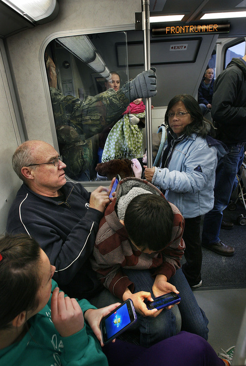 Scott Sommerdorf  |  The Salt Lake Tribune              
Bill Mitchell, along with his children Hanna and David, pass the time with their cellphones during the ride on the FrontRunner train between Provo and Salt Lake City. Mitchell said he was taking the ride to investigate if it was a good commuting option for him. The public was invited to ride the new FrontRunner line linking Provo and Salt Lake City, Saturday, December 8, 2012.
