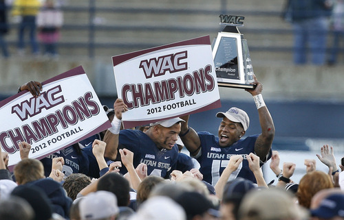 Scott Sommerdorf  |  The Salt Lake Tribune              
Utah State Aggies CB Will Davis (17), right, hoists the WAC trophy as his team mate WR Matt Austin holds aloft a WAC Champions sign after the win over Idaho. Utah State defeated Idaho 45-9 in Logan, Saturday, November 24, 2012 to become champions of the WAC.