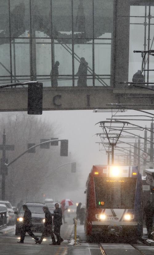 Al Hartmann  |  The Salt Lake Tribune
People cross Main Street in Salt Lake City between South Temple and 100 South during the noontime snowstorm as others stay dry walking through the enclosed City Creek Center skybridge.