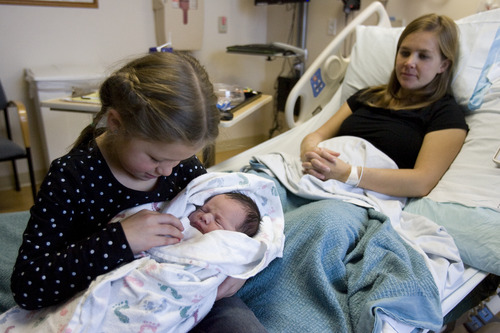 Kim Raff  |  The Salt Lake Tribune
(left) Sydney England holds her newborn sister (middle) Kate England with as her mother Brittany England looks on at Intermountain Medical Center in Murray on December 12, 2012. Kate was born at 1:44 am that morning.  "This was her actual due date and we didn't think we were gonna make it.  What a great due date," says Brittany England. The hospital gave commemorative onesies to the families of the newborns to celebrate the unique date.