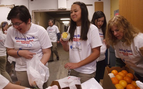 Leah Hogsten  |  The Salt Lake Tribune
Ogden Preparatory Academy student Ellie Putnam (center) and classmate Christina Gillespie make faces as they throw out moldy oranges while bagging the fruit.  Great Salt Lake Minerals Corporation's employees delivered four truckloads containing $27,000 worth of food to the Catholic Community Services Joyce Hansen Hall Food Bank Wednesday December 12, 2012 in Ogden, providing holiday food for nearly 2,000 Utah families. Students from the Ogden Preparatory Academy helped GSL Minerals volunteers unload the trucks and assemble food bags for needy families.