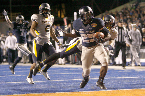 Chris Detrick  |  The Salt Lake Tribune
Utah State Aggies running back Kerwynn Williams (25) scores a touchdown past Toledo Rockets defensive back Cheatham Norrils (11) during the fourth quarter of the Famous Idaho Potato Bowl at Bronco Stadium Saturday December 15, 2012.  The Aggies beat the Rockets, 41-15.