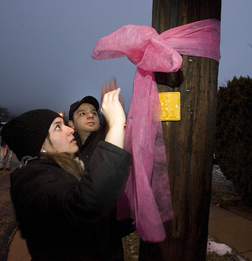 Paul Fraughton  |   Salt Lake Tribune
Friends of the Parker family, Jennifer and Julio Moraes,  hang a large pink ribbon on a telephone pole near the home of Randy Parker. They were joined by other friends and neighbors who  spread out over their Ogden neighborhood Monday night  hanging pink ribbons  to commemorate  young Emilie Parker, who was one of the children killed in the shooting at the Connecticut  elementary school.