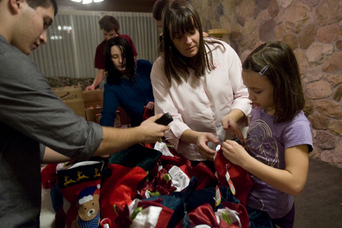 Kim Raff  |  The Salt Lake Tribune
Chrystal Butterfield helps Breann Burningham stuffs stockings for soldiers with her son (left) Chad Butterfield during a volunteer work day for the Stockings for Soldiers program at Redwood Cemetery in Taylorsville on November 29, 2012. Butterfield is a very active volunteer, on top of working full-time and raising three kids.