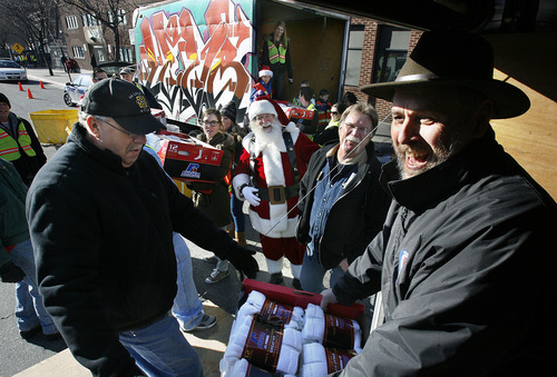 Scott Sommerdorf  |  The Salt Lake Tribune              
As Santa watches, Kevin Cote, right, of the Utah Plasterers & Cement Masons Local 568 hands a case of socks to Roy Adams as the Utah Building Trades and Utah Labor Community Services donated 4,956 new socks and 850 diapers to the residents of the Road Home on Thursday.