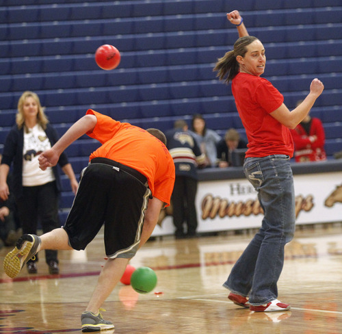 Al Hartmann  |  The Salt Lake Tribune
Lisa Jensen, psychology teacher hits student dodge ball player and dodges his last throw to win a championship match beteween students and faculty  at Herriman High School Hearts of Gold closing assembly on Friday December 21.   The assembly celebrated the season charity drive with everything from a dodge ball championship match to dances and student body skits. Through prior student donations and today's assembly the school raised $30,012,56 for charity.