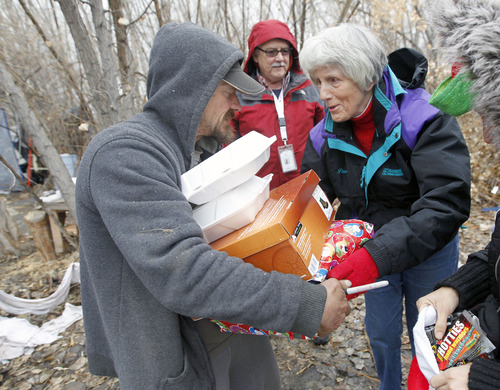 Al Hartmann  |  The Salt Lake Tribune
Homeless advocate Pamela Atkinson, right, and Ed Snoddy, medical outreach coordinator for Volunteers of America, middle, deliver a hot meal, boots and a warm coat to to "Scott" a homeless man who lives in a camp along the Jordan River Monday December 24.  The two visited homeless people around Salt Lake City offering hot meals, boots, and warm clothing to help get them through the cold weather.