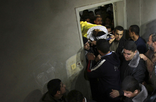 Palestinian relatives carry the body of Anwar Al-Mamlok, 22, into his family house during his funeral in Gaza City, Saturday, Jan. 12, 2013. The Israeli military shot and killed one Palestinian near the border fence with Gaza on Friday, an official in the territory said. The Israeli military said that Al-Mamlok was part of a group that rushed the fence to try to damage it adding that soldiers warned the Palestinians to back off before firing first into the air and then toward the men's legs. (AP Photo/Adel Hana)