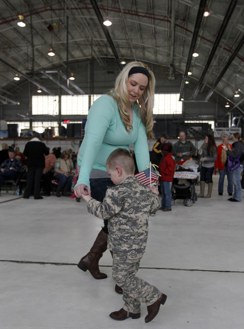 Al Hartmann  |  The Salt Lake Tribune
Alyssa McClellon dances to the band's music with one of her 3-year-old twin sons, Riley, while waiting for the arrival of their husband and father, Spc. Collin McClellan of the 1st Battalion, 211th Aviation after his 12-month deployment to Afghanistan.  Hundreds of friends and relatives greeted the 150 soldiers at the Utah Air National Guard Base in Salt Lake City Thursday.