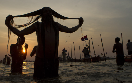 A Hindu devotee takes a holy bath at "Sangam," the meeting point of Indian holy rivers of Ganges, Yamuna and the mythical Saraswati, on occasion of "Paush Purnima," considered to be very auspicious according to Hindu calendars, during the Maha Kumbh festival in Allahabad, India, Sunday, Jan. 27, 2013. Hundreds of thousands of Hindu pilgrims are expected to take a ritual dip at Sangam on Sunday. Millions of Hindu pilgrims are likely to attend the Maha Kumbh festival, which is one of the world's largest religious gatherings that lasts 55 days and falls every 12 years. (AP Photo/Rajesh Kumar Singh)