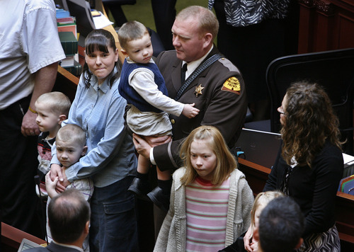 Scott Sommerdorf   |  The Salt Lake Tribune
Utah Highway Patrol Trooper Aaron Beesley was honored by speeches, a moment of silence and standing ovations before the Utah Legislature on, Wednesday, January 30, 2013. Trooper Aaron Beesely's widow Kristie Beesely is at left holding her son Derek (5), with his twin brother Preston at far left. Aaron's brother Arik, also a UHP trooper holds his sone Boston (1), as his daughter Afton (9) is beside him and his wife Julianne is at far right.
