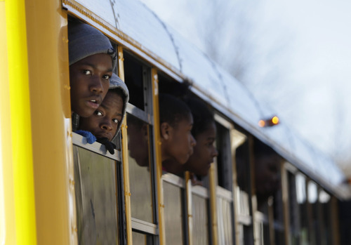 Children look out from a school bus as they are transported to their parents after a shooting at an Price Middle school in Atlanta Thursday, Jan. 31, 2013. A 14-year-old boy was wounded outside the school Thursday afternoon and a fellow student was in custody as a suspect, authorities said. No other students were hurt. (AP Photo/John Bazemore)