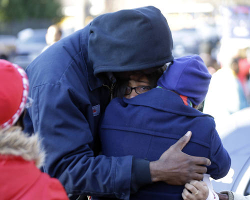 A man and a woman are reunited with a child a child after after a shooting at an Price Middle school in Atlanta Thursday, Jan. 31, 2013. A 14-year-old boy was wounded outside the school Thursday afternoon and a fellow student was in custody as a suspect, authorities said. No other students were hurt. (AP Photo/John Bazemore)
