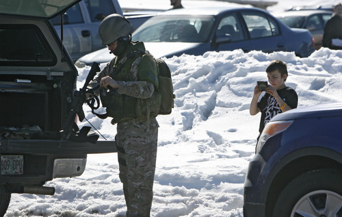 Francisco Kjolseth  |  The Salt Lake Tribune
A boy takes a cell phone photo of a SWAT team member in Kearns as armed officers from the Unified Police Officer swarmed a nearby residence where a man had allegedly holed up inside a residence with his wife and baby. The man was taken into custody after a three-hour standoff and no one was injured. The nearby Western Hills Elementary School was placed on lockdown during the incident.