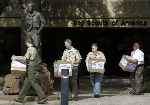 FILE - In this Feb. 4, 2013, photo Eagle Scout Will Oliver, from left, former Scoutmaster Greg Bourke, former den leader Jennifer Tyrrell and Eric Andresen, right, a parent of a gay scout deliver boxes filled with a petition to the statue in front of the Boy Scouts of America headquarters in Irving, Texas. The Boy Scouts of America's policy excluding gay members and leaders could be up for a vote as soon as Wednesday, when the organization's national executive board meets behind closed doors under intense pressure from several sides. (AP Photo/Tony Gutierrez, File)