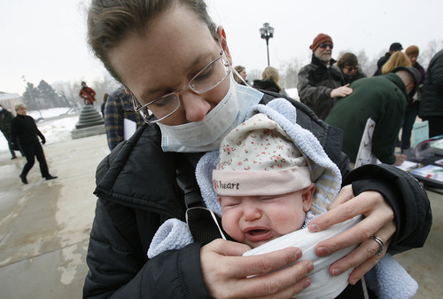Scott Sommerdorf   |  The Salt Lake Tribune
Kelsey Garner attempts to fit a mask on her 12-week-old baby girl, Mae, prior to participating in the clean air rally on the south steps of the Capitol building, Wednesday, February 6, 2013.