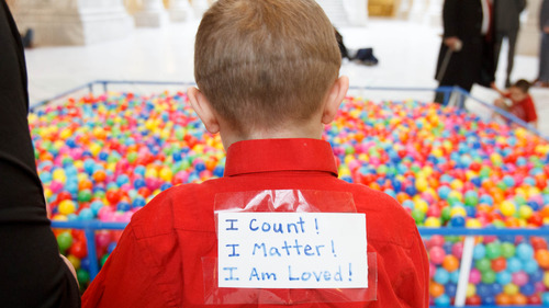 Trent Nelson  |  The Salt Lake Tribune
Davis Pauley wears a sign saying "I count! I matter! I am loved!" near a pit of 18,532 plastic balls, one ball for every autistic child in Utah. Advocates for autism insurance reform placed the huge display in the Capitol rotunda on Friday.