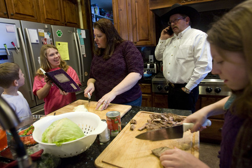 Kim Raff  |  The Salt Lake Tribune
As Denney Simmons watches, sister Annie shows her adopted mother, Amy Simmons, her writing as Sarah, right, helps in the kitchen at their home in Kamas on January 24, 2013. John Simmons is at center. John and Amy Simmons have nine children with five adopted from Russia, including Annie, Denney and Sarah.