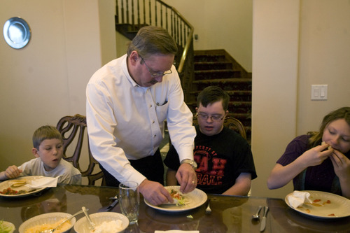 Kim Raff  |  The Salt Lake Tribune
John Simmons helps his son Jack with dinner as Denne, left, and Sarah eat at their home in Kamas on January 24, 2013.  John and Amy Simmons have nine children with five adopted from Russia, including Sarah and Denney.