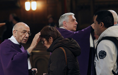 Al Hartmann  |  The Salt Lake Tribune
Deacon Silvio Mayo, left, and his son, Monsignor Joseph Mayo, make the sign of the cross in ash on the foreheads of Catholic faithful at the Cathedral of the Madeleine on Wednesday, Feb. 13 as part of an Ash Wednesday observance.