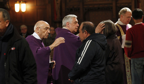 Al Hartmann  |  The Salt Lake Tribune
Deacon Silvio Mayo, left, and his son Reverend Msgr. Joseph Mayo make the sign of the cross in ash on the foreheads of Catholic faithful at the Cathedral of the Madeleine in Salt Lake City on Wednesday, Feb. 13 as part of an Ash Wednesday observance.