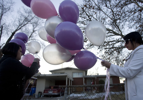 Kim Raff  |  The Salt Lake Tribune
(left) Lindsay and Beth Atwood friends of Danielle Lucero tie balloons outside the gate of the house where Lucero, Omar Jarman and Shontay Young were victims of a fatal shooing days earlier during a candle light vigil for the victims in Midvale on February 17, 2012.
