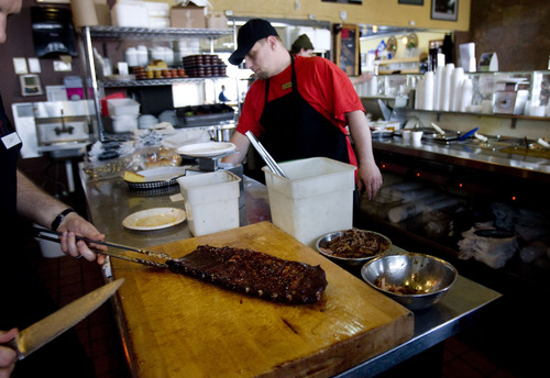 Kim Raff  |  The Salt Lake Tribune
Manager Jeffrey Berg slices up a rack of ribs at Sugarhouse BBQ Company in Salt Lake City on Friday, February 22, 2013. Sugarhouse BBQ Company is moving to 2100 S. 900 East. Owners say the Trolley project will cut down on their parking so they will be forced to move from their current location at 2207 S. 700 East.