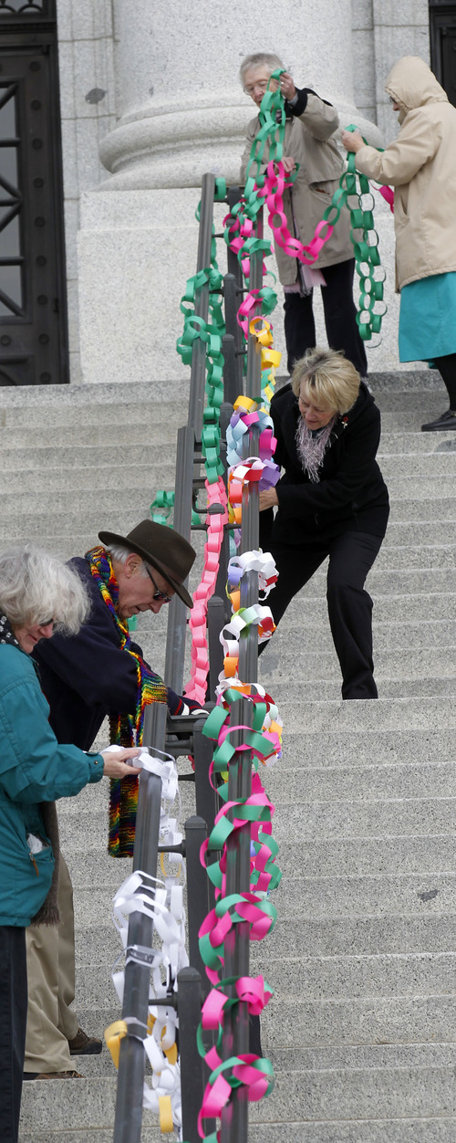Al Hartmann  |  The Salt Lake Tribune
Crossroads Urban Center, the Coalition of Religous Communities and  low-income advocates attach chains of paper links to handrails on the Utah State Capitol steps Friday.  The links represent the 150,000 Utahns that will be affected if Gov. Gary Herbert doesn't opt into Medicaid expansion under the Affordable Care Act.  After a rally the paper link chains were taken down and delivered to Herbert's office inside the capitol.